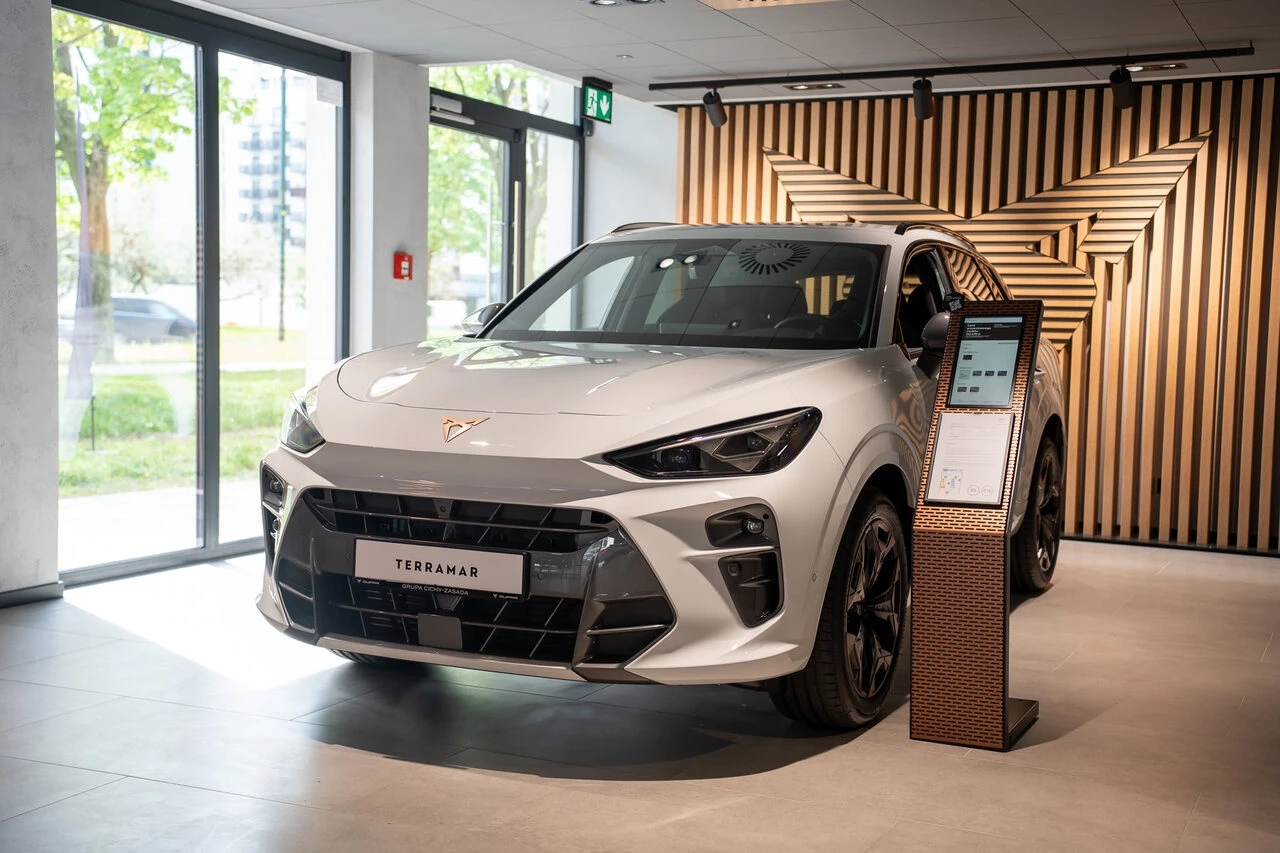 Nowa CUPRA Terramar w kolorze białym na tle drewnianego logotypu marki