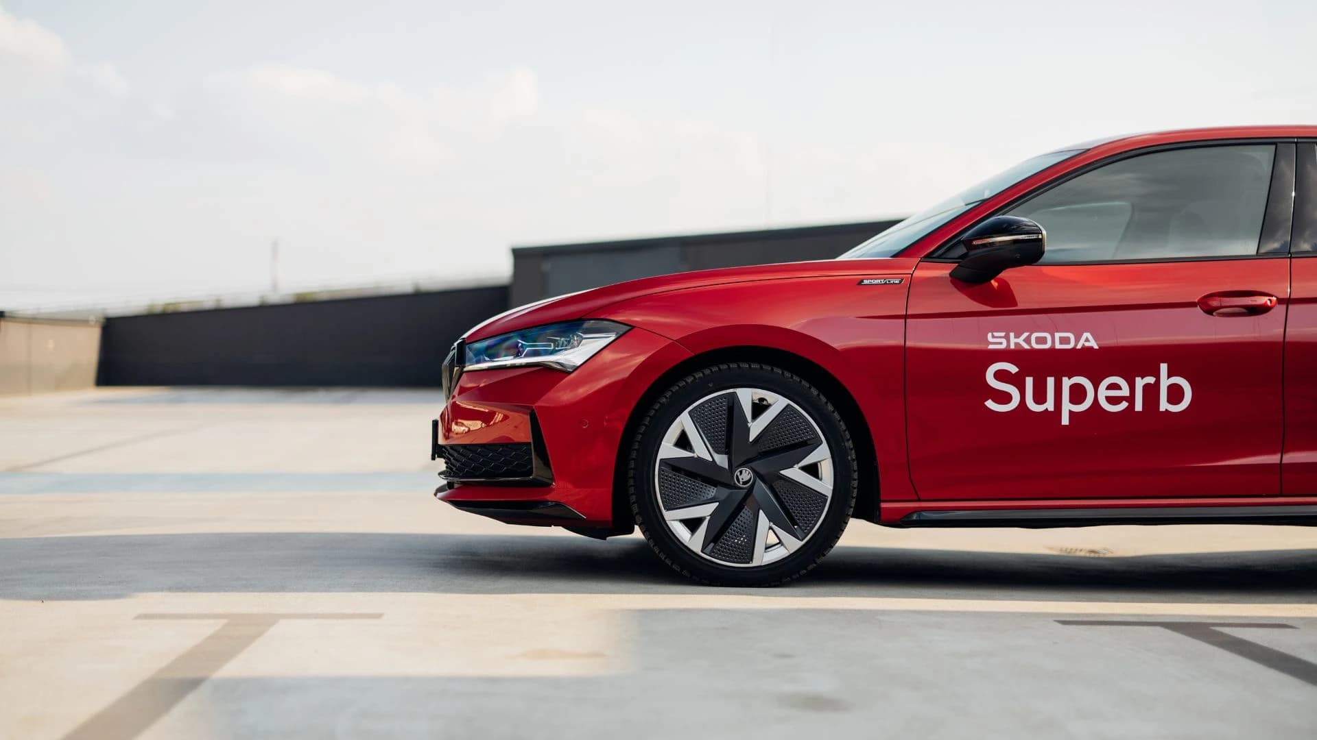 Czerwona Skoda Superb na tle parkingu