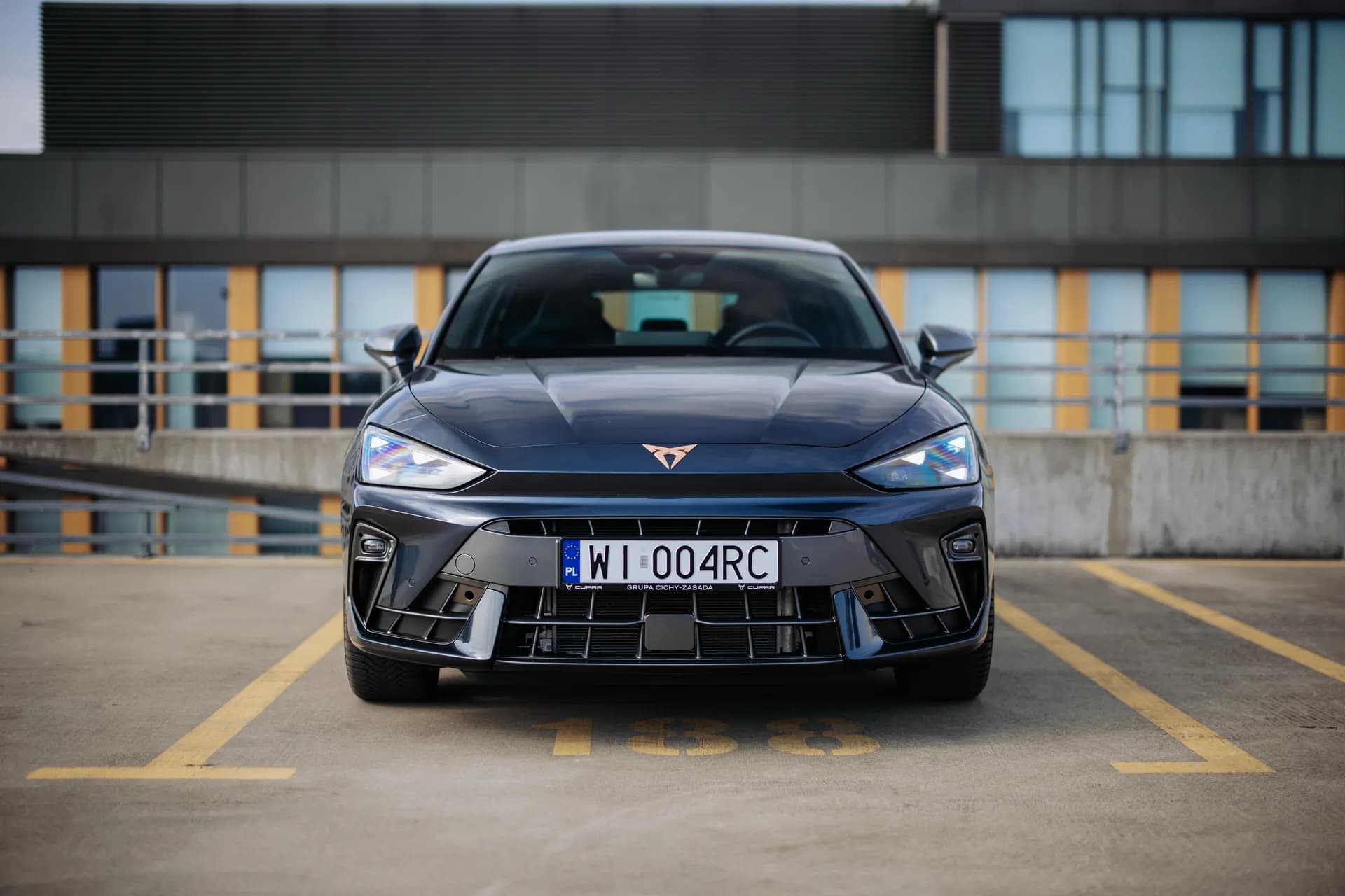 Przód szarej Cupra Born na parkingu z ramką Grupa Cichy-Zasada