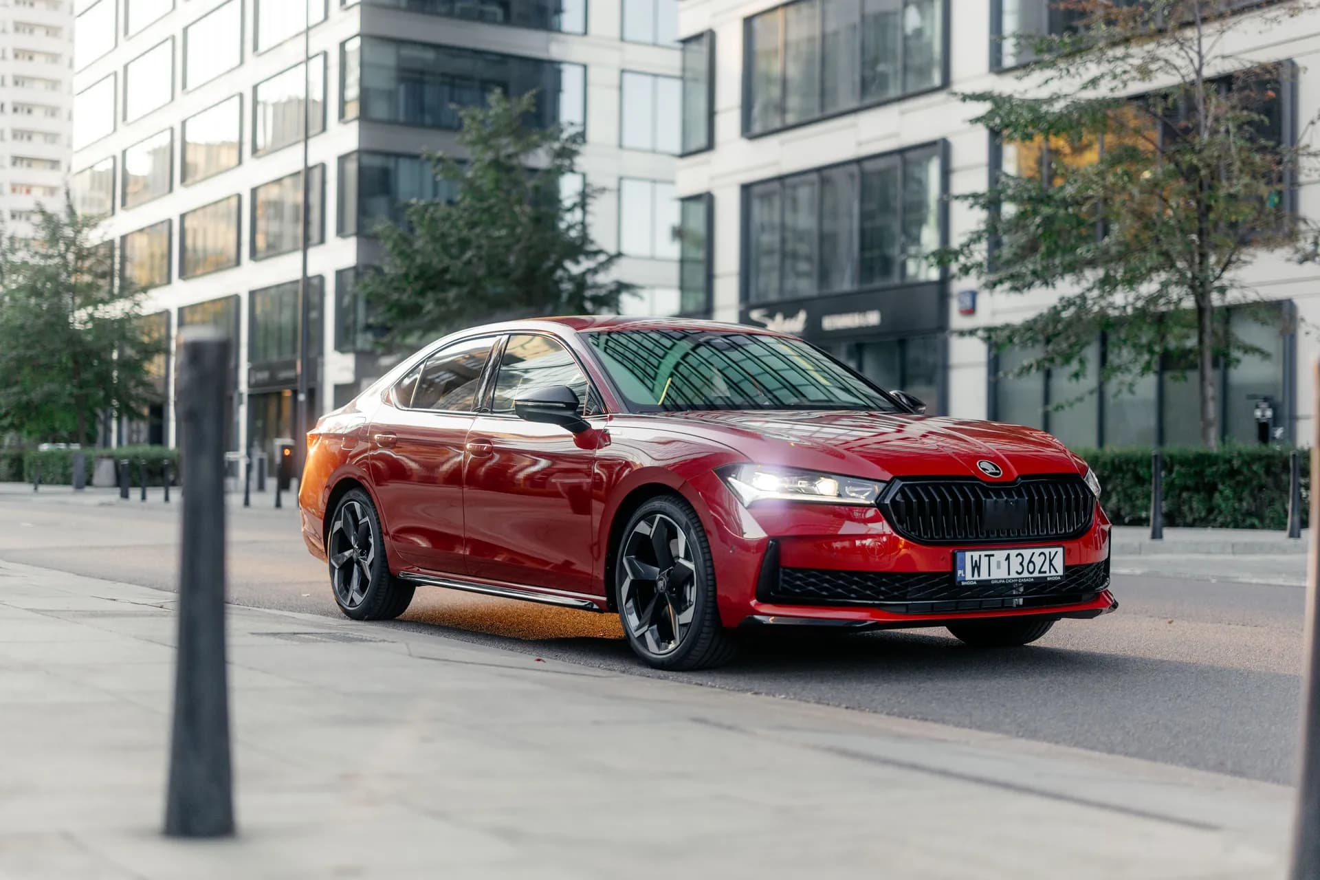 Czerwona Skoda Superb na ulicy na tle nowoczesnych biurowców