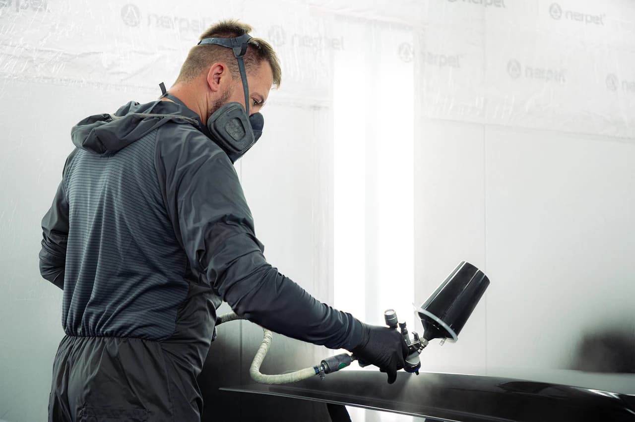 Pracownik blacharni w trakcie lakierowania