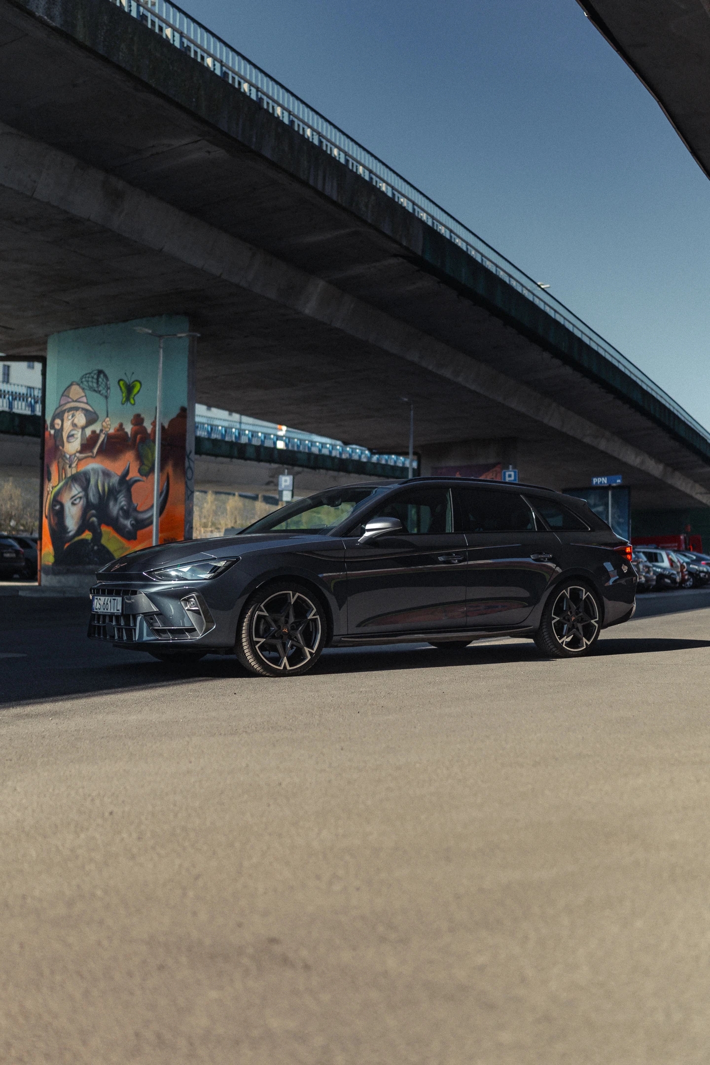 Nowa CUPRA Leon Sportstourer na tle mostów opatrzonych komiksowym grafitti