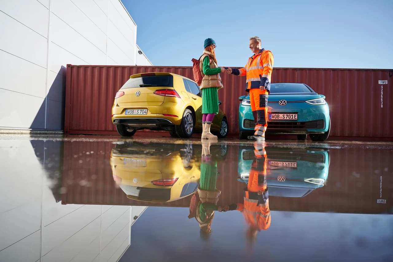 Kobieta i mężczyzna wypełniają oświadczenie sprawcy kolizji. W tle samochód Volkswagen.